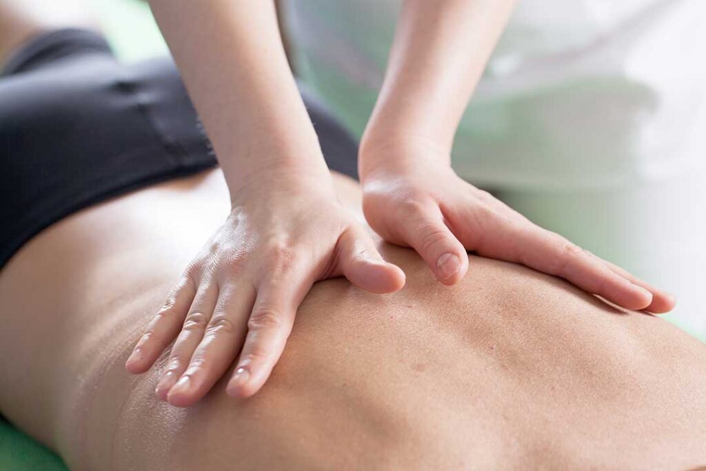Person gently stretching their back in a sunlit living room, showing mild self-care after chiropractic adjustment.